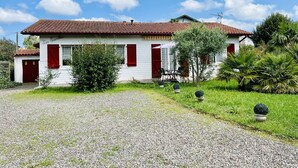 A white house with a red-tiled roof, red shutters, and a gravel driveway. - T3 House in Cambo, Pets Allowed, Parking, Internet (Cambo-les-Bains)