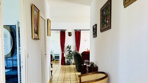 A narrow hallway with a chair, a potted plant, and a door leading to a bathroom. - T3 House in Cambo, Pets Allowed, Parking, Internet (Cambo-les-Bains)