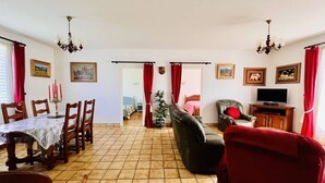 A spacious living room with a dining area, a sofa, a television, and a potted plant. - T3 House in Cambo, Pets Allowed, Parking, Internet (Cambo-les-Bains)