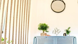 Ein Zimmer mit einer Schnurvorhang, einem runden Spiegel und einem blauen Metallregal mit Pflanzen und Dekoration.