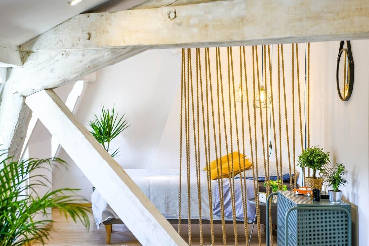 Un dormitorio acogedor con una cama, una planta colgante y una mesita con una planta y un modelo de coche.