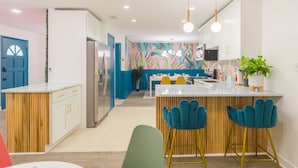 Una cocina moderna con armarios blancos, una isla de madera y taburetes azules.