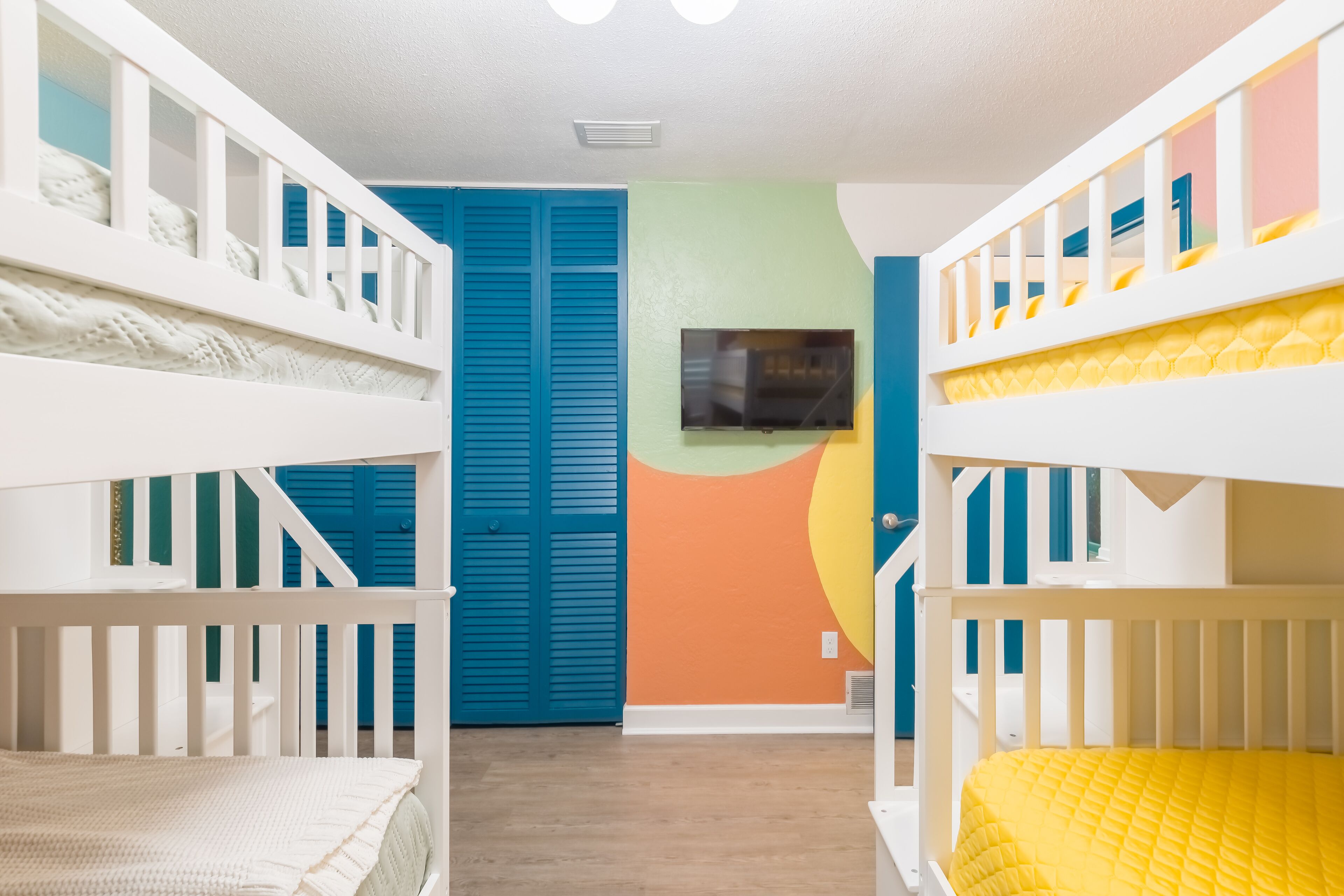 Ein Kinderzimmer mit Etagenbetten, einem Fernseher und einer farbenfrohen Wand.