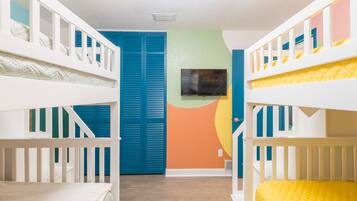Ein Kinderzimmer mit Etagenbetten, einem Fernseher und einer farbenfrohen Wand.