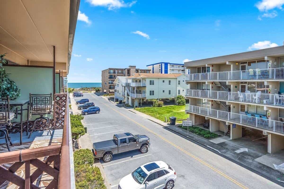 Um hotel com vários andares, varandas, estacionamento e vista para o mar.