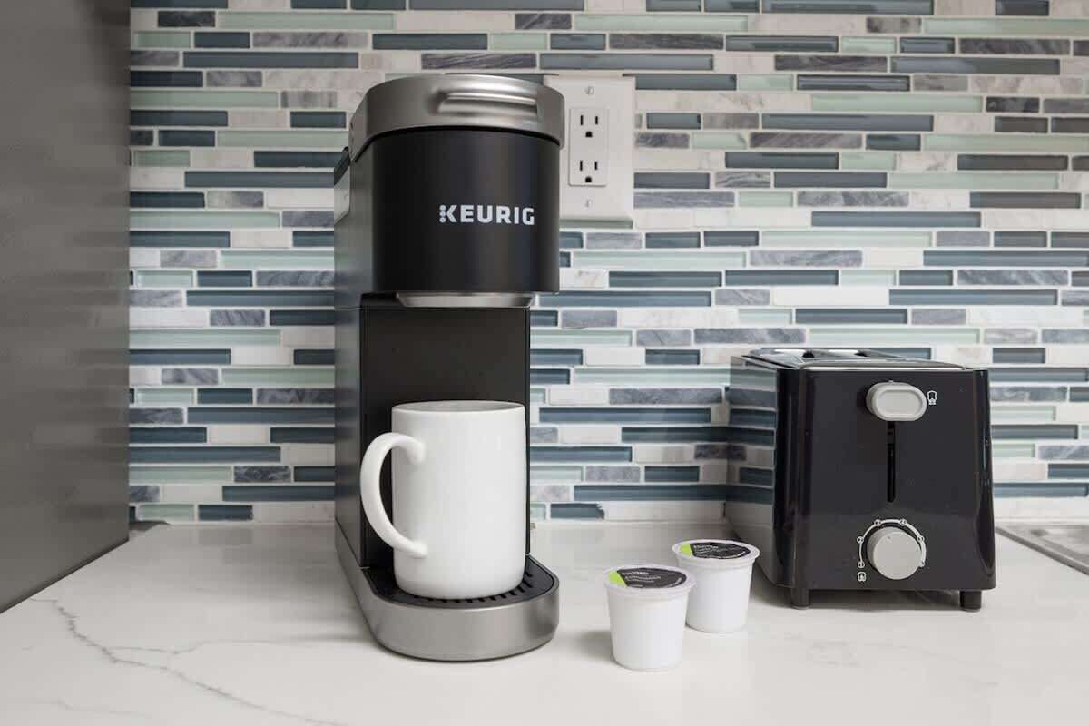 A Keurig coffee maker with a white mug and two coffee pods on a countertop.