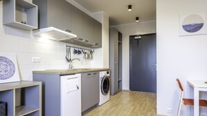 Une cuisine compacte équipée d’un lave-linge, d’un évier et d’un coin repas avec une chaise.