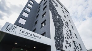 Un grand immeuble sur lequel on peut lire l’inscription « Eduard House, par Larsen Apartments ».