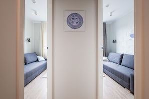 Et moderne hotelværelse med lysegråt gulv, en grå sofa, et vægmaleri og en væg af hvide mursten.