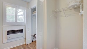 A room with a white radiator, a window with blinds, a door leading to a closet, and a white wall-mounted shelf with a basket. - 2 beds, Kitchenette, Free Parking - Room 2 (Tequesta)