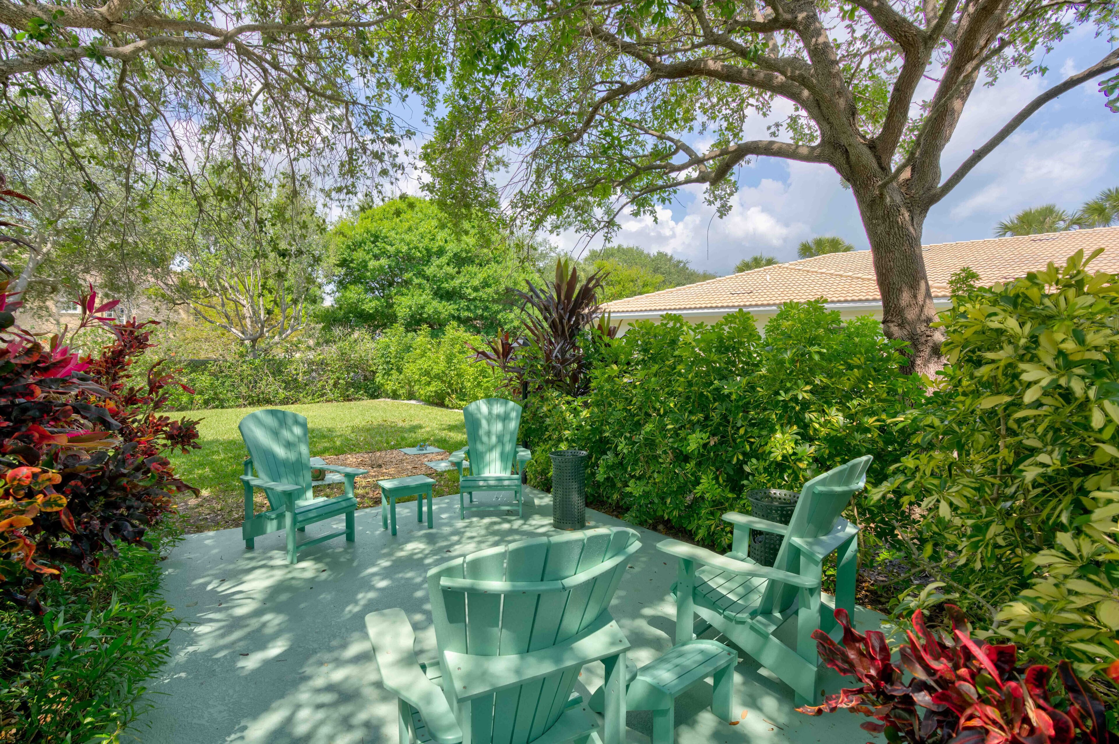 Une terrasse extérieure avec des fauteuils Adirondack verts et une petite table.