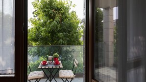 A balcony with a table, two chairs, and potted plants.