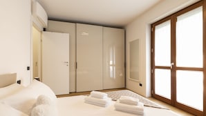 A modern bedroom with a large bed, a wardrobe, and a sliding glass door to a balcony.