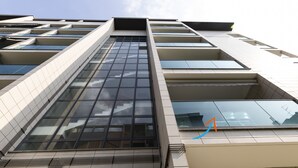 A modern building with a prominent glass facade, multiple balconies, and a geometric design.