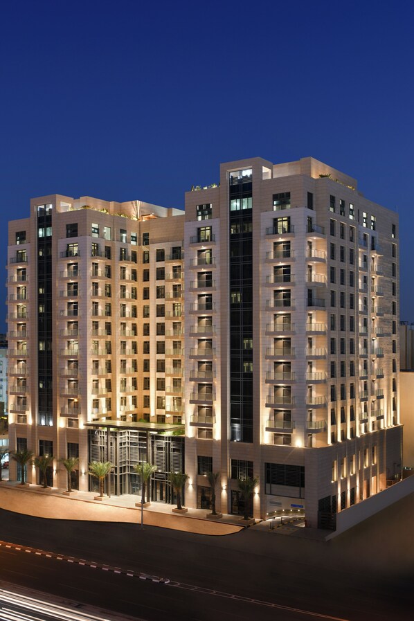 A high-rise hotel with multiple floors, balconies, and a well-lit entrance area.