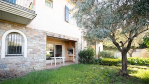 A stone building with a patio, a table, and a tree. - Casa Vacanze Cecilia (Manerba del Garda)