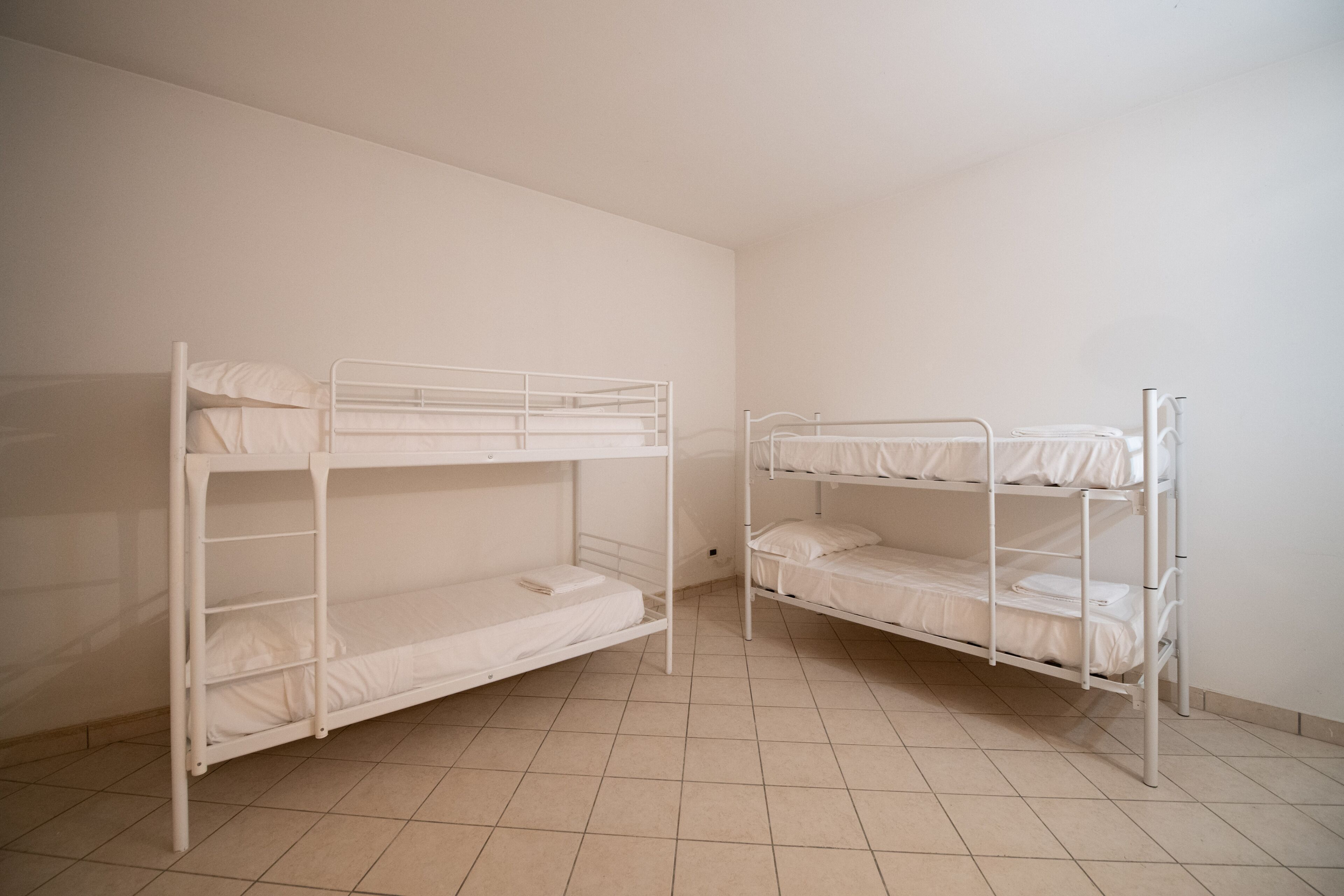 Two bunk beds in a room with tiled flooring and white walls.