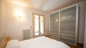 A bedroom with a bed, a radiator, a wardrobe, and a door leading to an outdoor area. - Casa Vacanze Cecilia (Manerba del Garda)