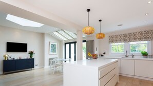Een moderne keuken met een centraal eiland, hangende lampen en een dakraam.