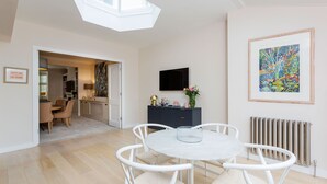 Een moderne eetruimte met een ronde tafel, witte stoelen en een dakraam.