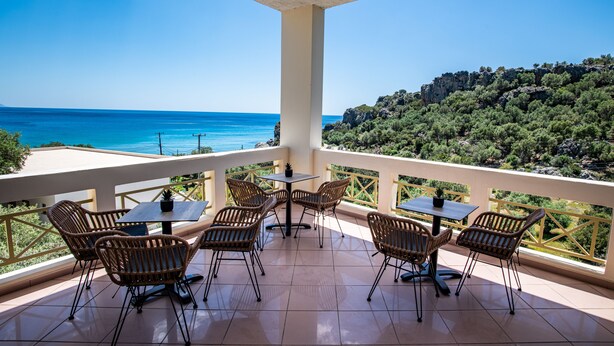 Una terraza con mobiliario de mimbre y vista al mar.