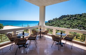 A terrace with wicker furniture and a view of the sea. - Polyrizos Hotel (Agios Vasileios)
