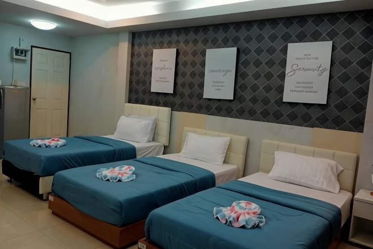 Quarto de hotel com três camas, um guarda-roupa e uma parede com citações motivacionais emolduradas.