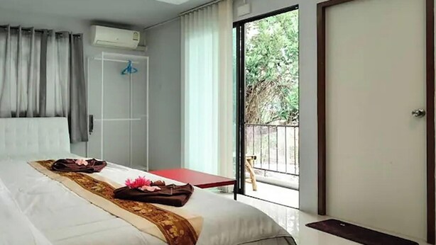 Een moderne hotelkamer met een groot bed, een kleine tafel en een schuifglazen deur naar een buitengebied.