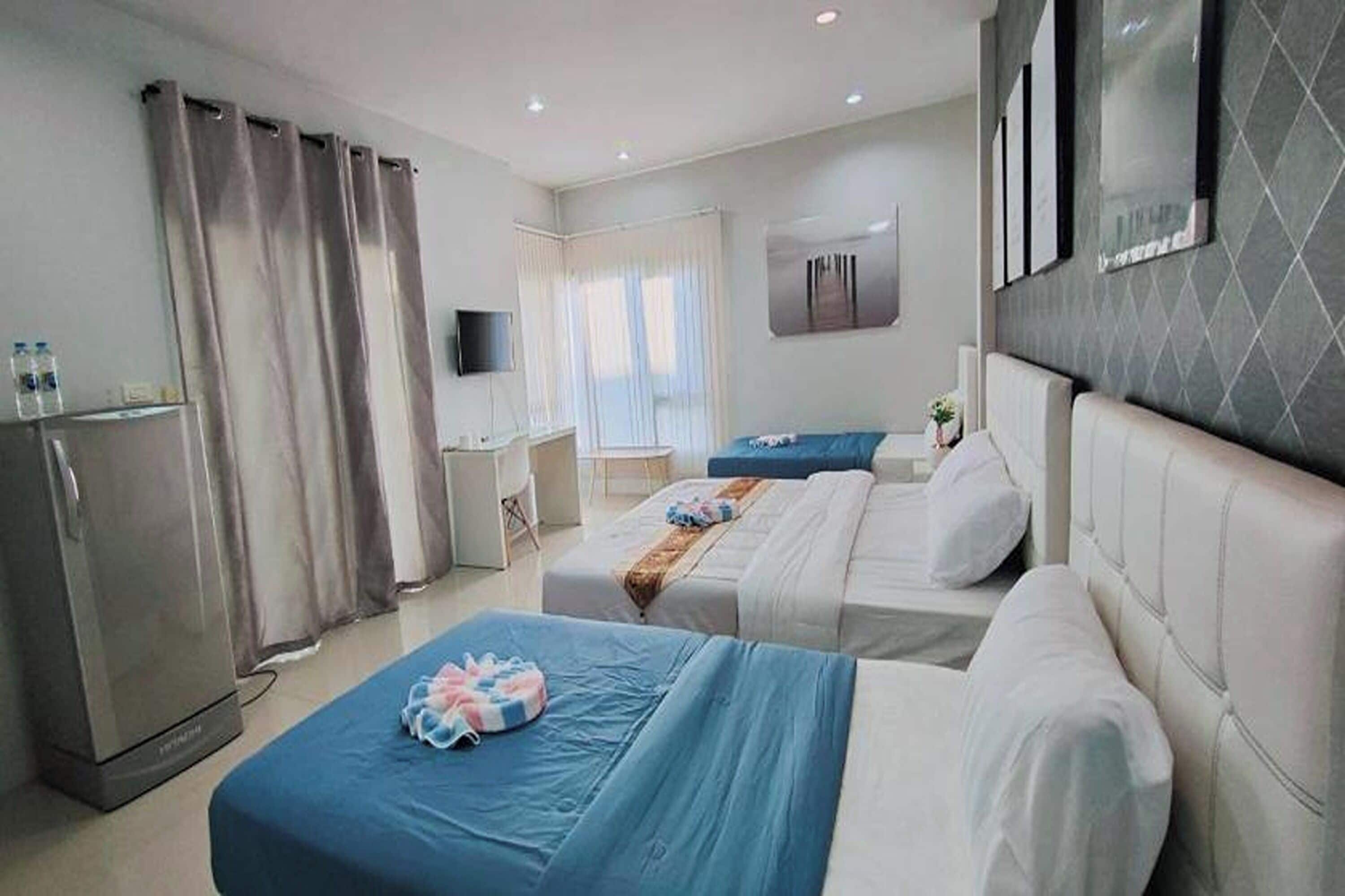 A hotel room with two beds, a desk, a television, and a wardrobe.