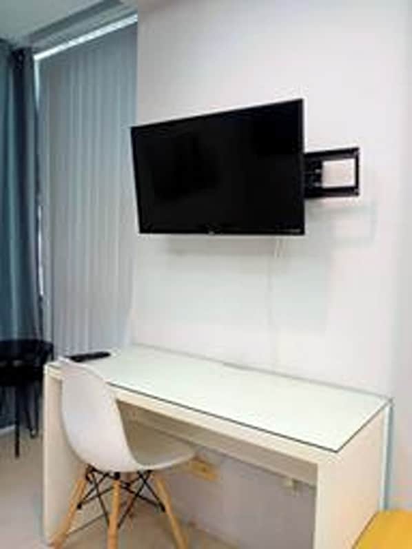 A modern room with a white desk, a chair, and a mounted flat-screen TV.