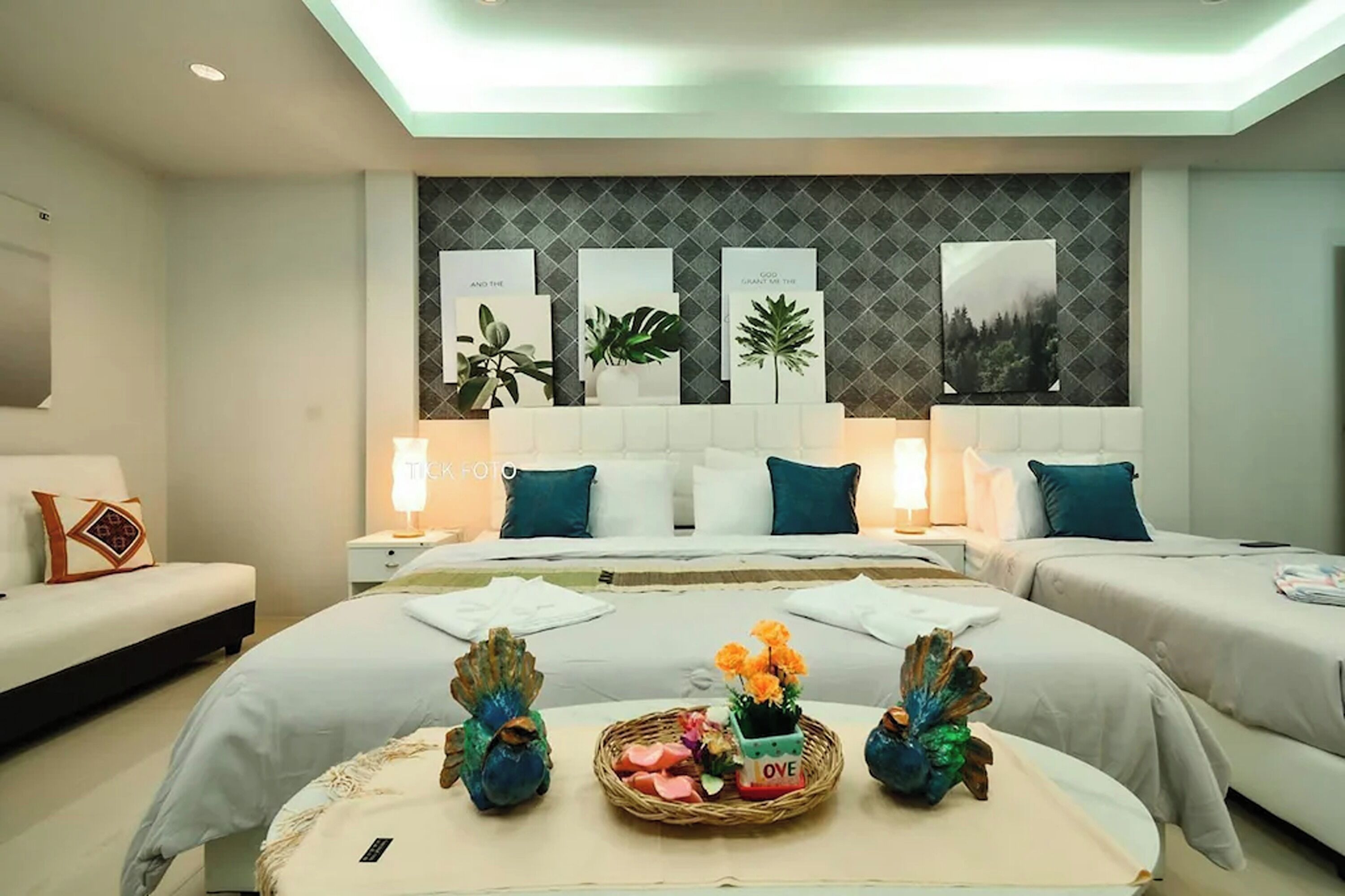 Una habitación de hotel con una cama grande, dos mesitas de noche, un sofá y una pared decorada con cuadros.