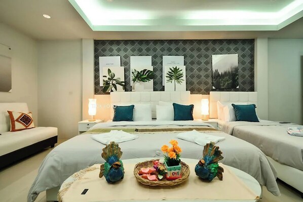 A hotel room with a large bed, two bedside tables, a sofa, and a wall with framed pictures.