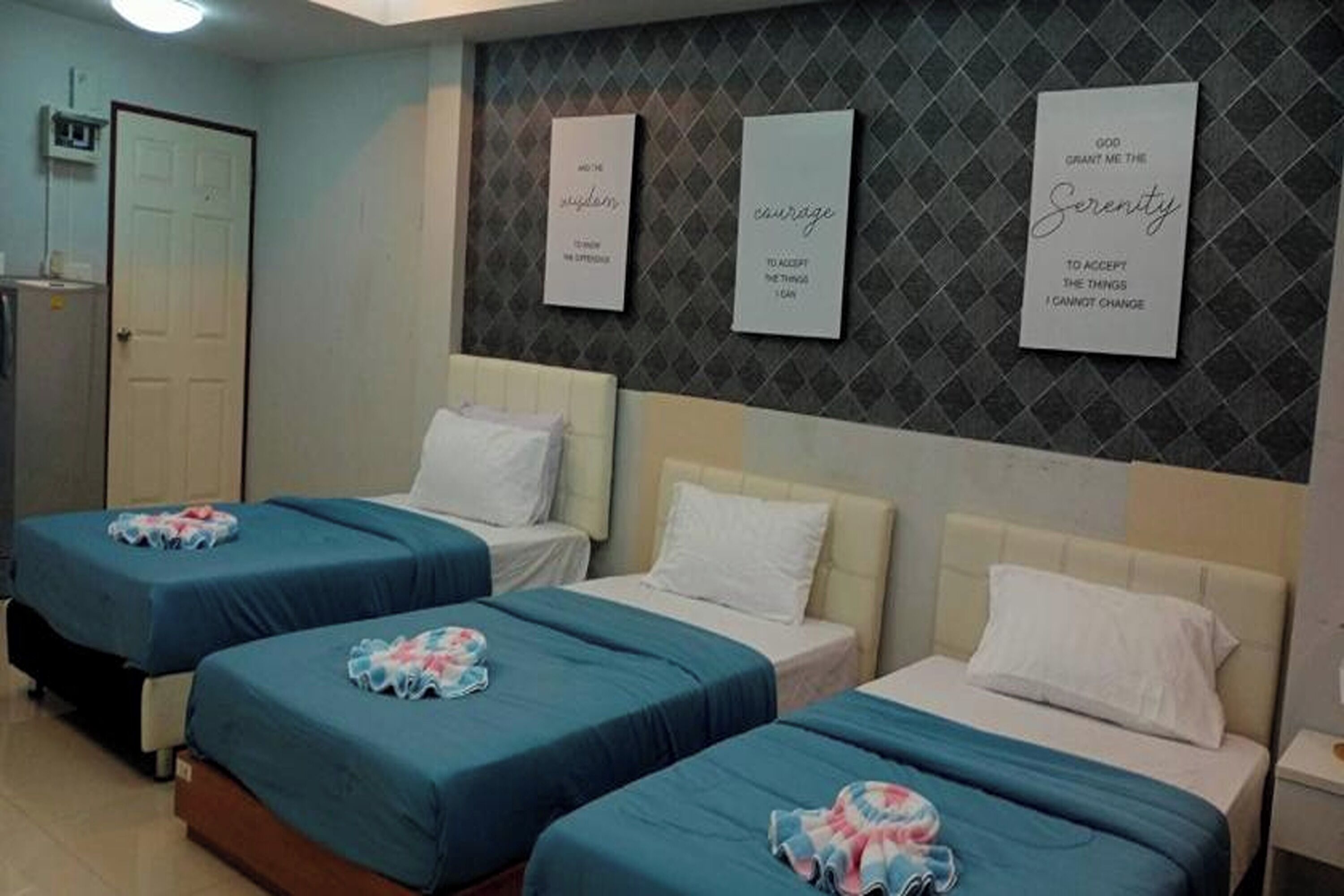 Ein Hotelzimmer mit drei Betten, jedes mit einem anderen Kopfteildesign.