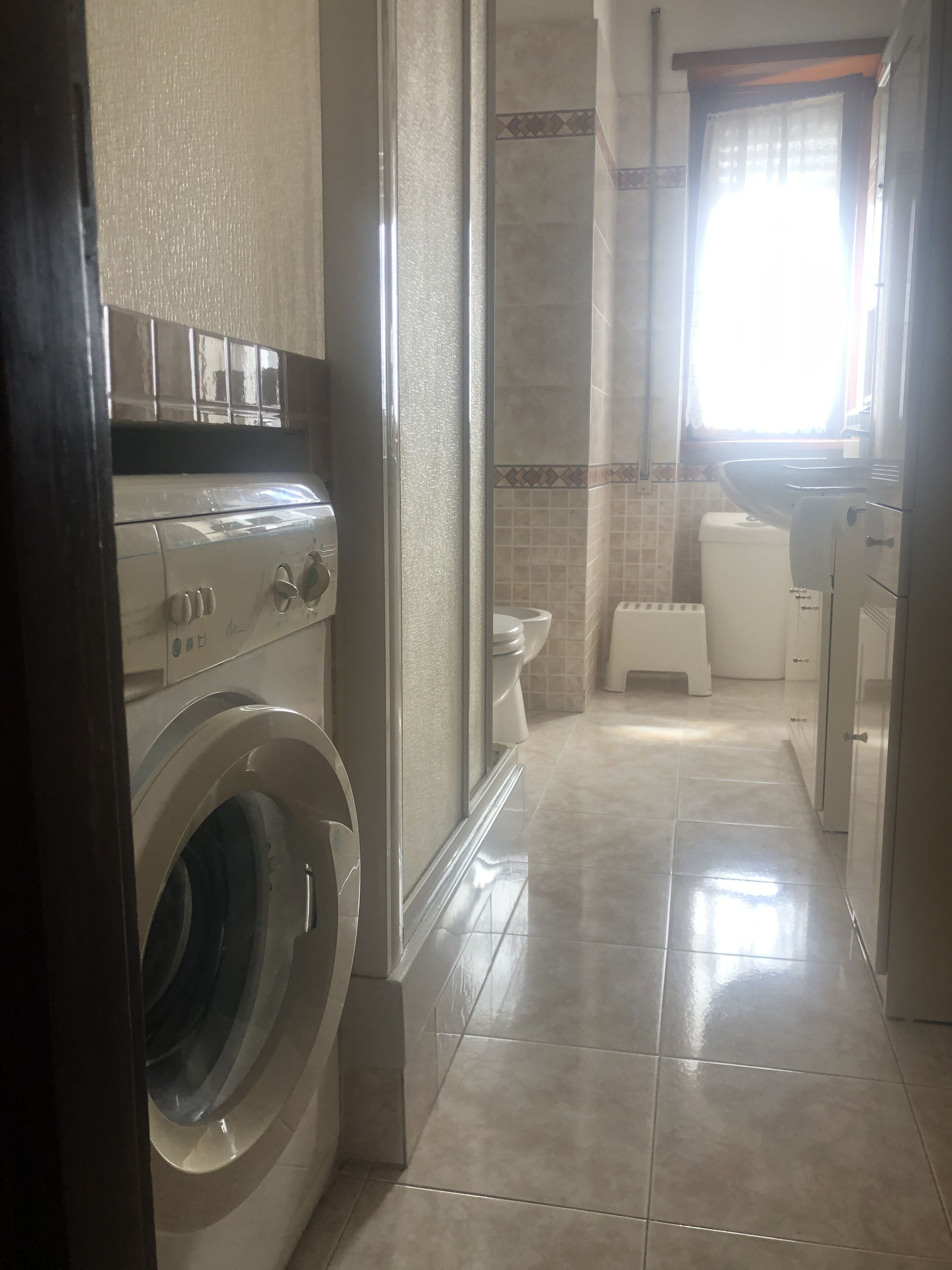 Ein Waschbereich mit Waschmaschine und Trockner, ein gefliester Duschbereich und eine Toilette.