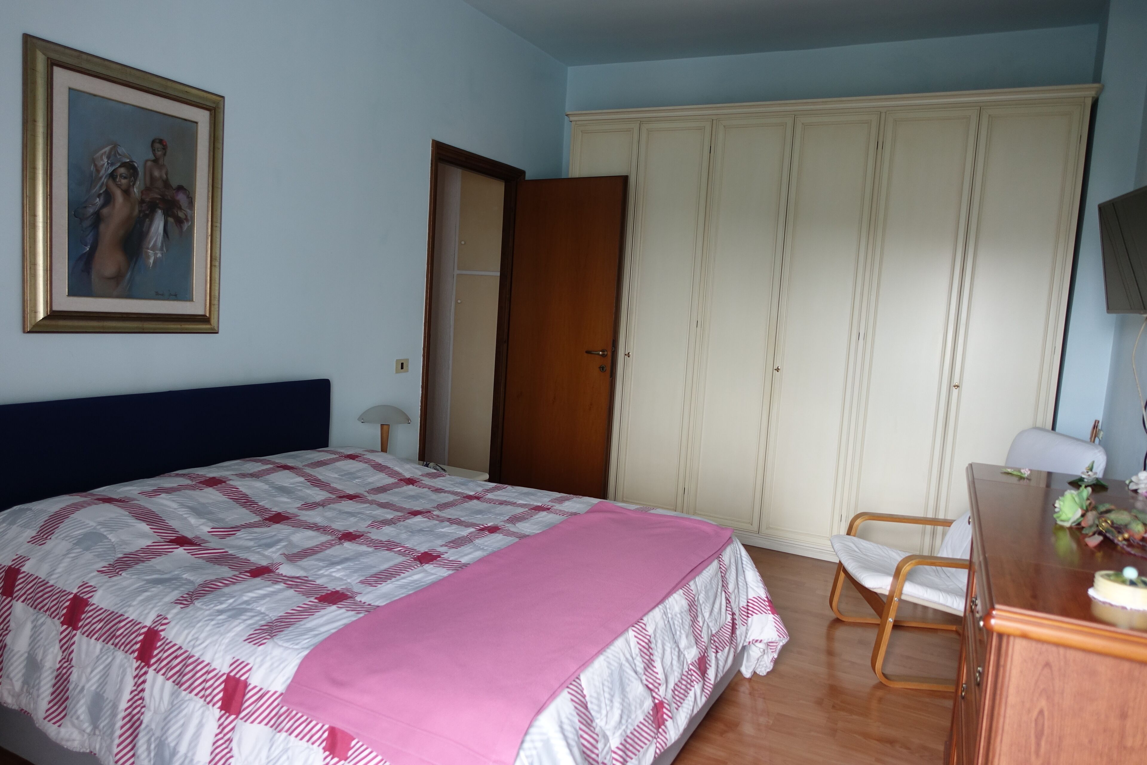 A bedroom with a bed, a wardrobe, a desk, and a chair.