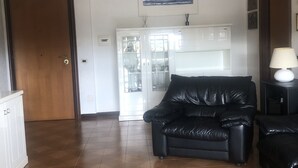A living room with a black leather sofa, a white cabinet, and a white cabinet with glass doors.