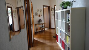 A hallway with a wooden floor, a white bookshelf, and a small table with a vase.