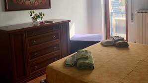 A bedroom with a bed, a dresser, a painting, and an air conditioning unit.