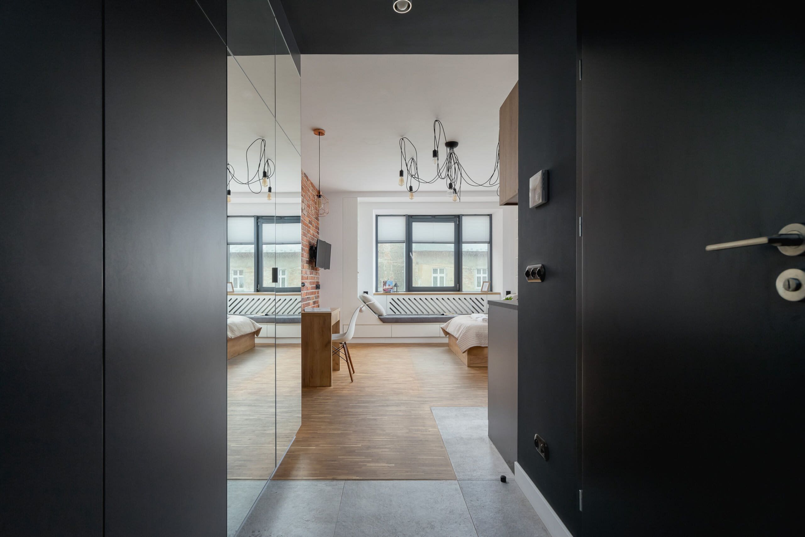 A modern bedroom with a large window, a wooden floor, and a bed with a white headboard.