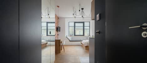 Un dormitorio moderno con un ventanal grande, suelo de madera y cama con cabecero blanco.