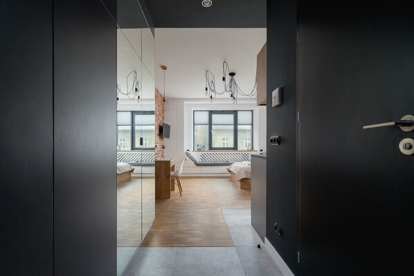 A modern bedroom with a large window, a wooden floor, and a bed with a white headboard.