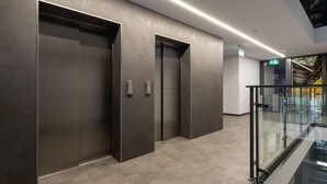 A modern elevator area with metallic walls and glass railings.