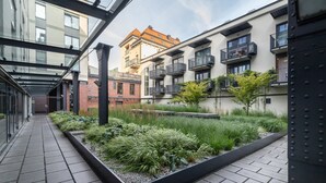 A modern building with a glass walkway, outdoor garden, and multiple balconies.