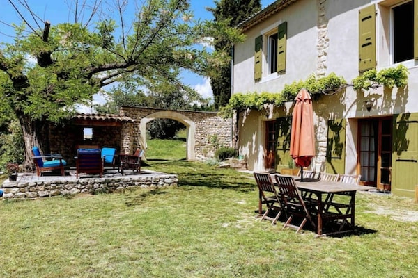 Extérieur, coin salon de jardin et coin repas avec parasol.