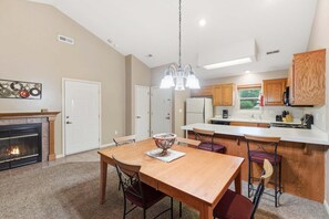 A kitchen with wooden cabinets, a dining table with chairs, a chandelier, and a fireplace.