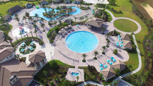 Ein Resort mit mehreren Schwimmbecken, Liegestühlen und Palmen.
