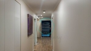 A narrow hallway with a wooden floor, white walls, and a door at the end. - ZEN AT ROSEWOOD - 2BR Guesthouse & Pool (Leanyer)