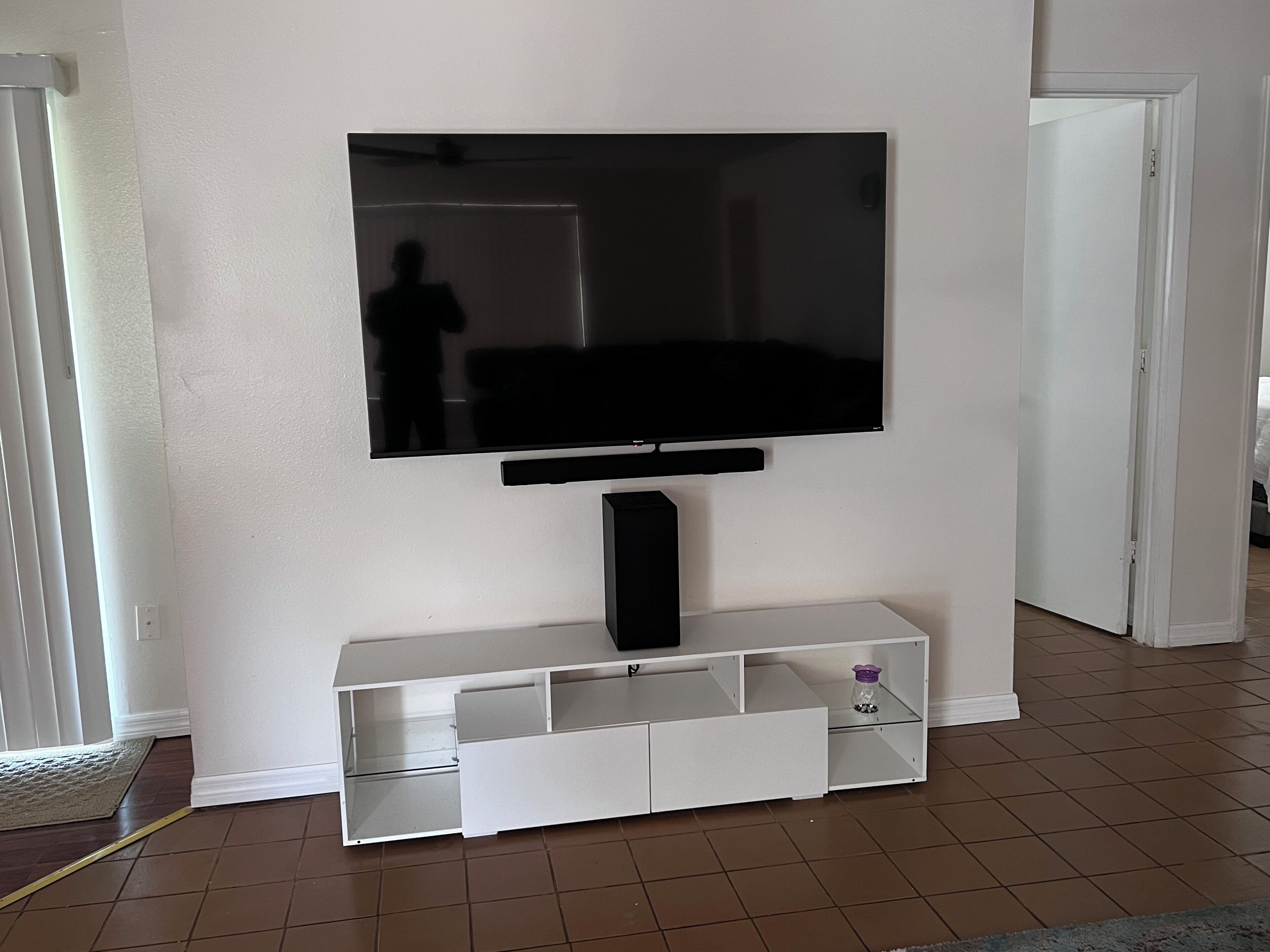 A white entertainment unit with a flat-screen TV mounted above it.