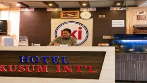 Bancada de recepção do Hotel Kusum International com um relógio, bandeiras e um aquário.