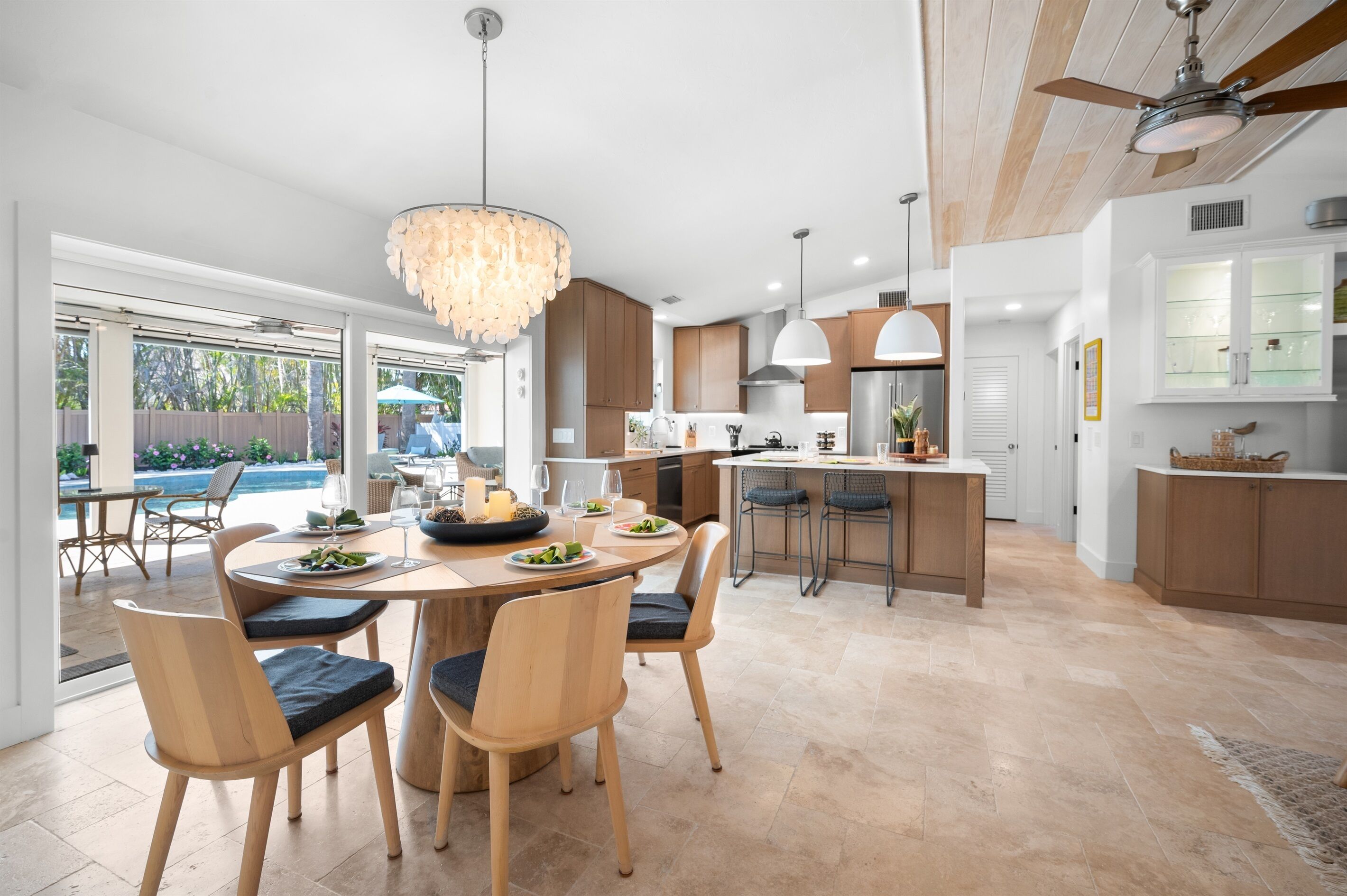 A modern kitchen with wooden cabinets, a central island, and pendant lighting.